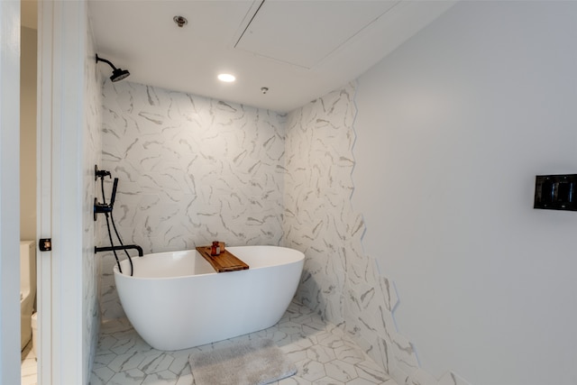 bathroom with a tub to relax in and toilet