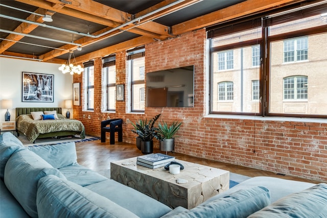 living room featuring an inviting chandelier, a wealth of natural light, brick wall, and hardwood / wood-style floors