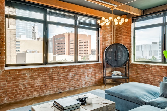 living room with an inviting chandelier, parquet flooring, and brick wall