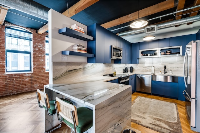 kitchen featuring sink, light parquet flooring, appliances with stainless steel finishes, brick wall, and blue cabinetry