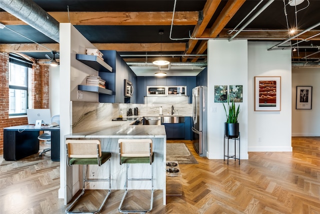 kitchen with kitchen peninsula, light parquet flooring, brick wall, stainless steel appliances, and a breakfast bar