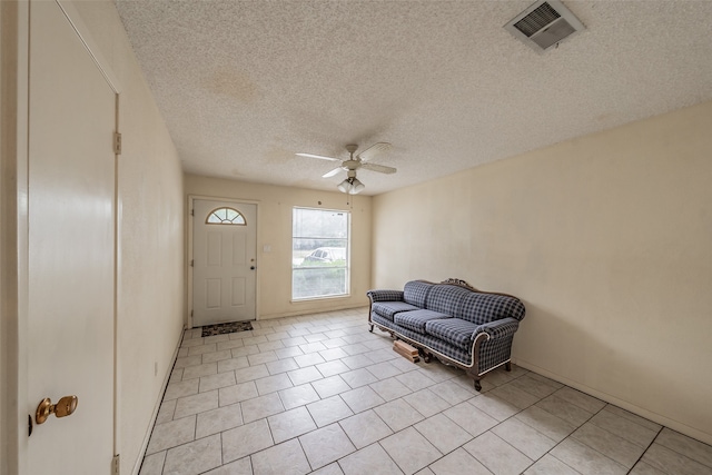 tiled entrance foyer with ceiling fan and a textured ceiling