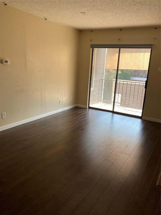 empty room featuring dark hardwood / wood-style flooring and a textured ceiling