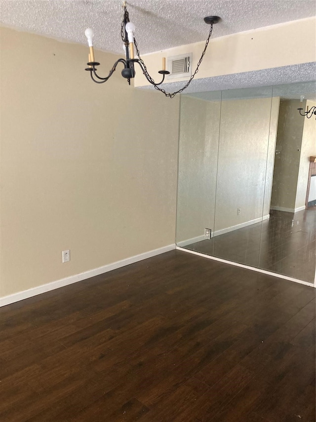 interior space with a textured ceiling, dark hardwood / wood-style floors, and an inviting chandelier