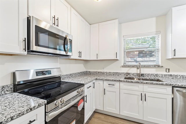 kitchen featuring sink, light stone countertops, white cabinets, and appliances with stainless steel finishes