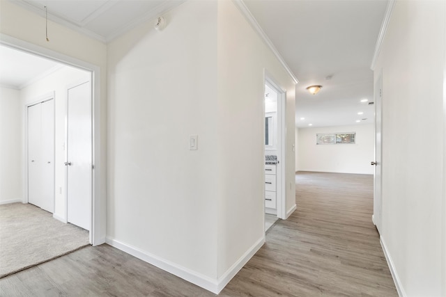 corridor with ornamental molding and light wood-type flooring