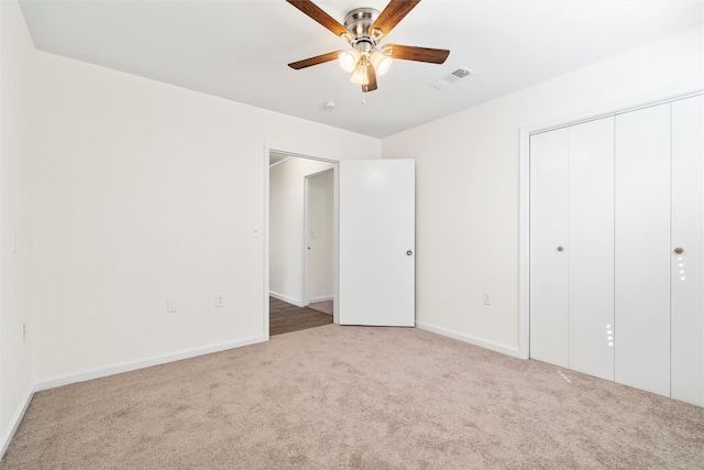 unfurnished bedroom with light carpet, ceiling fan, and a closet