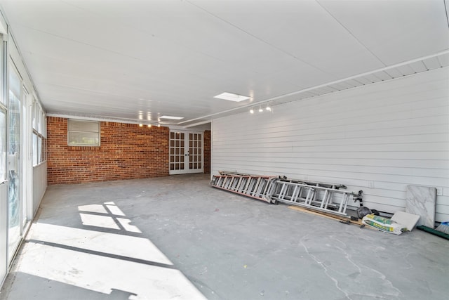 spare room with concrete floors, brick wall, and wood walls