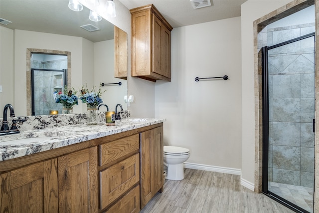 bathroom with vanity, toilet, hardwood / wood-style flooring, and a shower with shower door