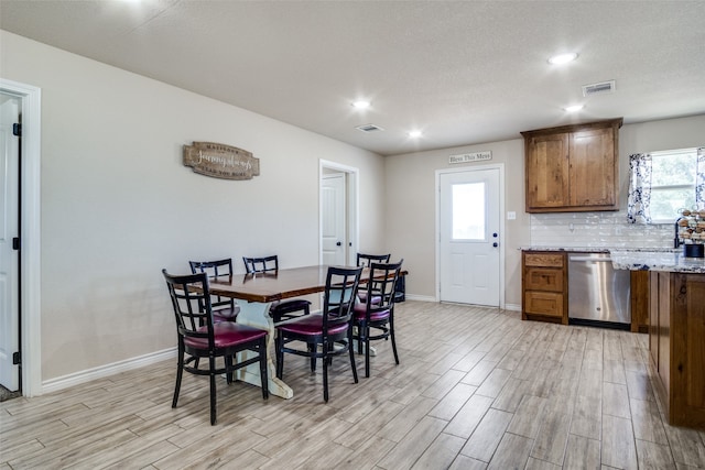 dining room with plenty of natural light, light hardwood / wood-style floors, and a textured ceiling