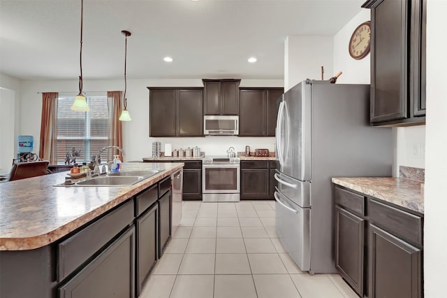 kitchen featuring a kitchen island with sink, pendant lighting, dark brown cabinets, sink, and appliances with stainless steel finishes