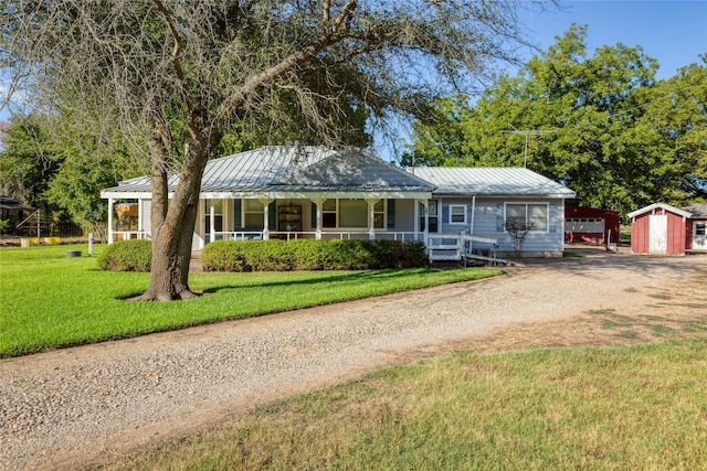 view of front of home with a storage shed, a front yard, and a porch