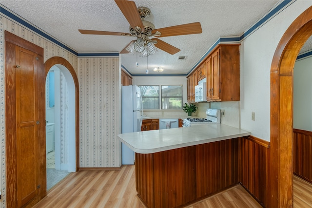 kitchen with kitchen peninsula, light wood-type flooring, and white appliances