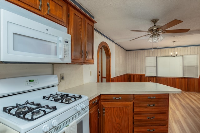 kitchen featuring light wood-type flooring, ceiling fan with notable chandelier, white appliances, kitchen peninsula, and a textured ceiling