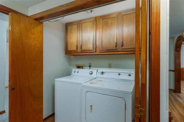 laundry room with cabinets, washer and clothes dryer, and light wood-type flooring