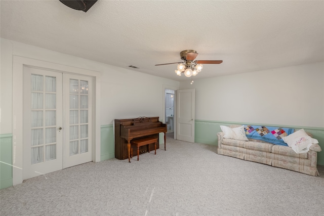 living room with a textured ceiling, carpet flooring, and ceiling fan