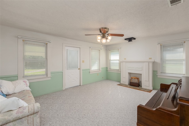 living room with a textured ceiling, ceiling fan, and carpet floors