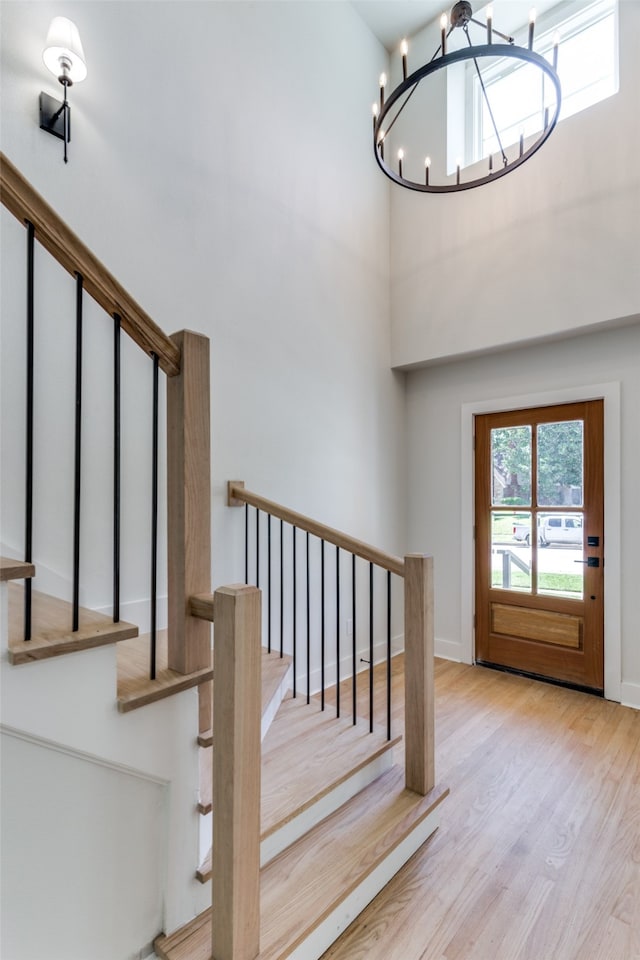 foyer entrance with a high ceiling, a notable chandelier, and light wood-type flooring