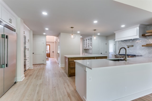 kitchen featuring built in appliances, decorative backsplash, white cabinets, and light hardwood / wood-style floors