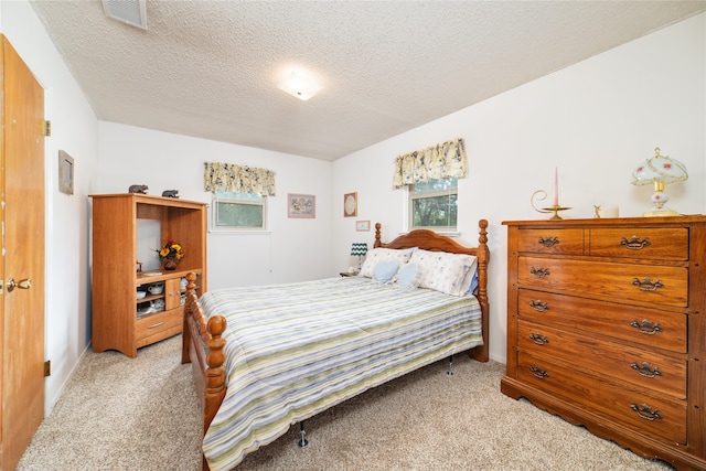 bedroom featuring a textured ceiling and light colored carpet