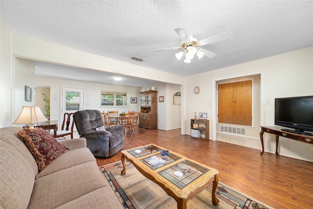 living room featuring a textured ceiling, hardwood / wood-style floors, and ceiling fan