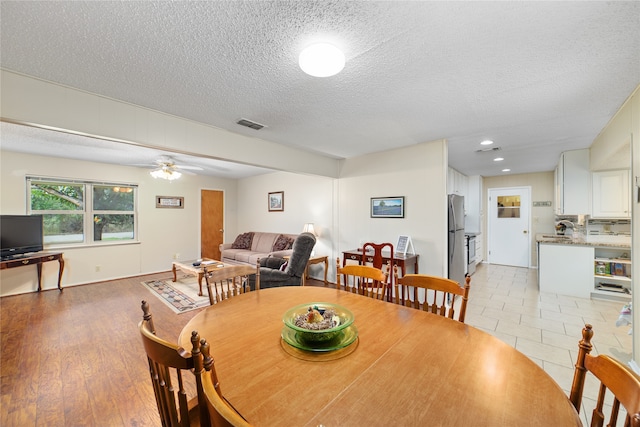 dining space with a textured ceiling, light hardwood / wood-style flooring, ceiling fan, and sink