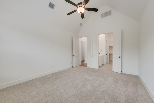 unfurnished bedroom with ensuite bathroom, high vaulted ceiling, light colored carpet, and ceiling fan