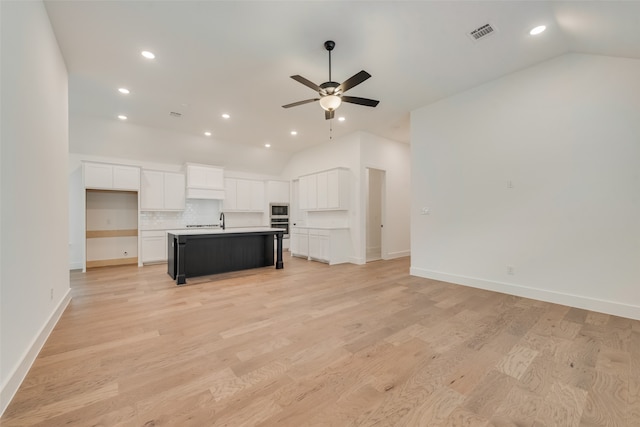 unfurnished living room with light hardwood / wood-style floors, ceiling fan, and vaulted ceiling