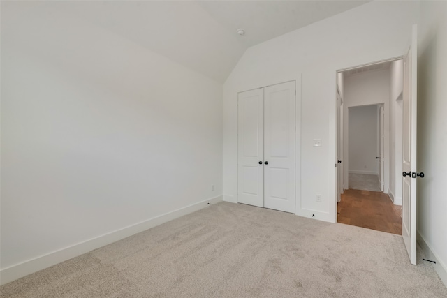 unfurnished bedroom with a closet, lofted ceiling, and carpet floors