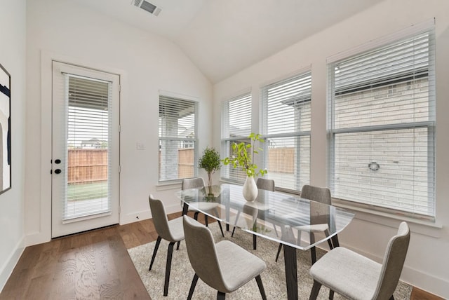 dining space with dark wood-type flooring, plenty of natural light, and vaulted ceiling