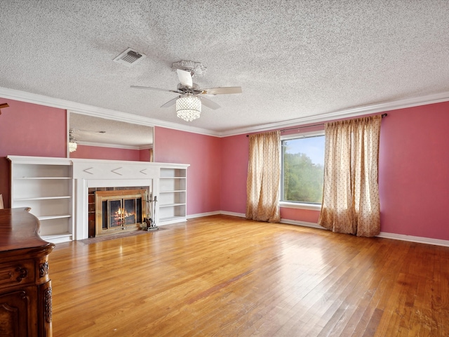 unfurnished living room featuring a fireplace, crown molding, a textured ceiling, ceiling fan, and light hardwood / wood-style floors