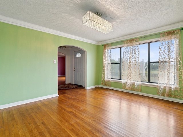 empty room with wood-type flooring, ornamental molding, and a textured ceiling