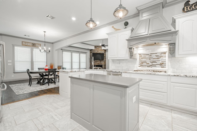 kitchen with a fireplace, stainless steel appliances, light hardwood / wood-style floors, pendant lighting, and a kitchen island