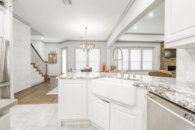 kitchen featuring light wood-type flooring, a fireplace, an inviting chandelier, sink, and appliances with stainless steel finishes