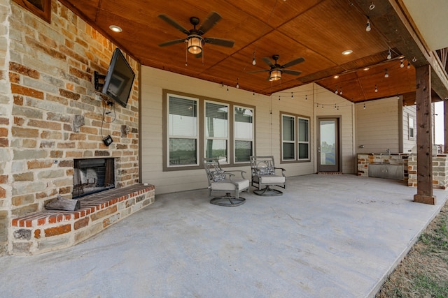 view of patio with ceiling fan and an outdoor brick fireplace