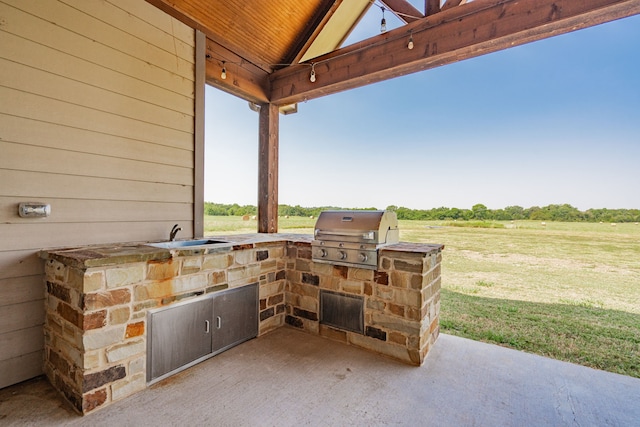 view of patio / terrace featuring area for grilling, an outdoor kitchen, a rural view, and sink