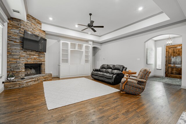 living room with a fireplace, a raised ceiling, ceiling fan with notable chandelier, and hardwood / wood-style flooring