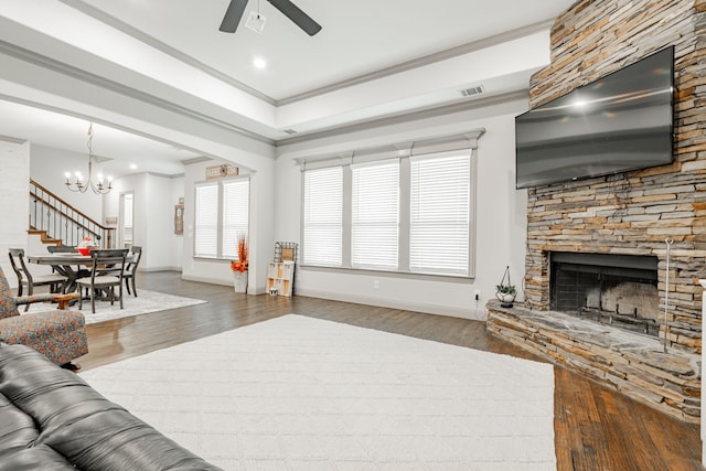 living room with ornamental molding, ceiling fan with notable chandelier, hardwood / wood-style flooring, and a fireplace