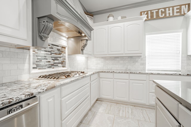 kitchen with crown molding, white cabinetry, stainless steel appliances, decorative backsplash, and custom range hood