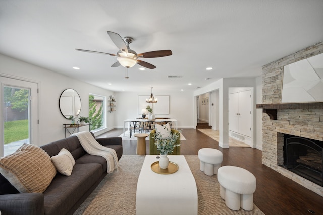 living room featuring dark hardwood / wood-style flooring, a fireplace, and ceiling fan with notable chandelier