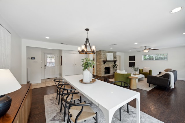 dining area with ceiling fan with notable chandelier, dark hardwood / wood-style floors, and a fireplace