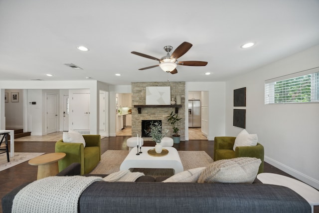 living room with a stone fireplace, ceiling fan, and hardwood / wood-style flooring