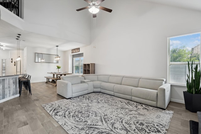 living room featuring ceiling fan with notable chandelier, plenty of natural light, and light hardwood / wood-style floors