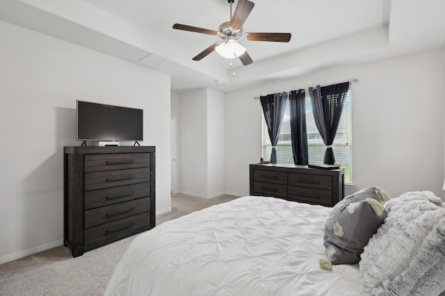 carpeted bedroom with a raised ceiling and ceiling fan