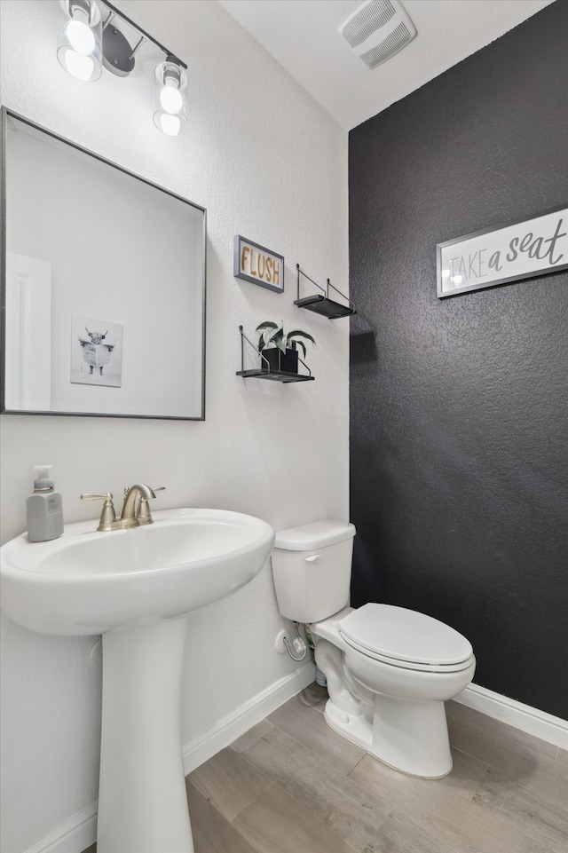 bathroom featuring toilet, sink, and wood-type flooring