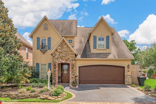 view of front of house with stucco siding, stone siding, a garage, and driveway