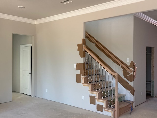 stairs with crown molding and concrete floors