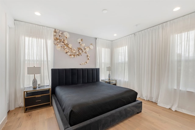 bedroom with multiple windows and light hardwood / wood-style flooring