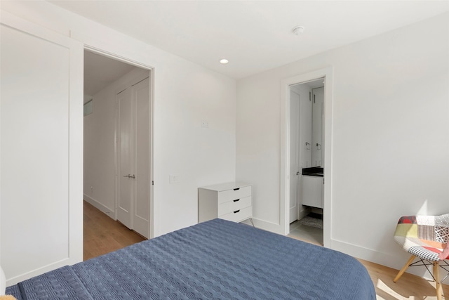 bedroom with connected bathroom and light hardwood / wood-style floors