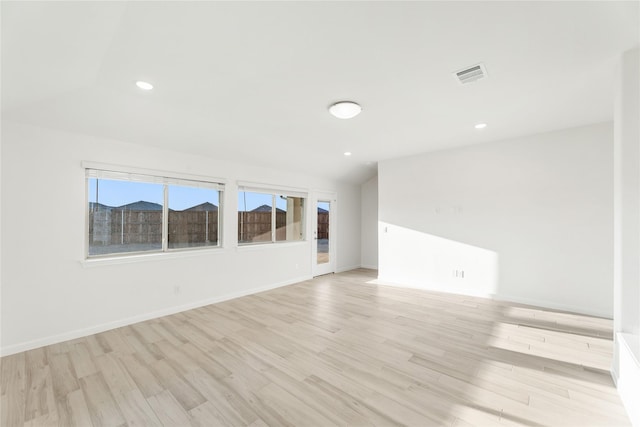 spare room with lofted ceiling and light hardwood / wood-style floors